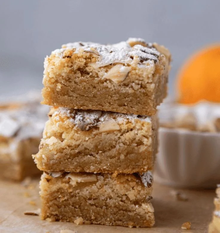 Delicious Almond Croissant Blondies on a wooden table, topped with almond slivers.