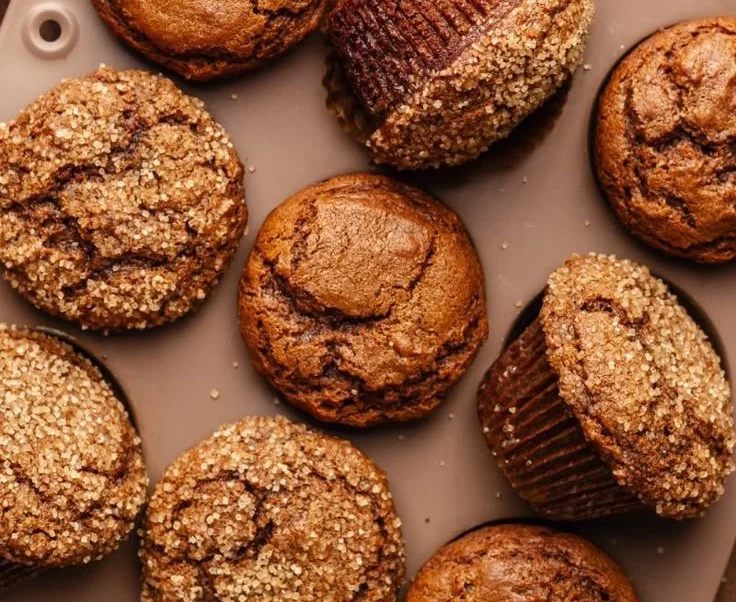 Homemade gingerbread muffins topped with icing on a wooden table.