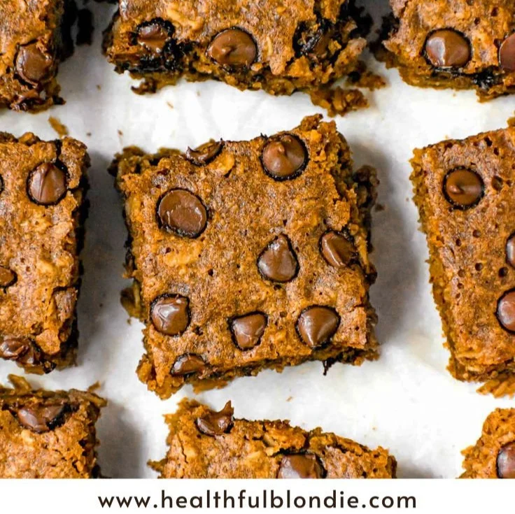 Healthy pumpkin oatmeal bars topped with nuts and seeds on a wooden table.
