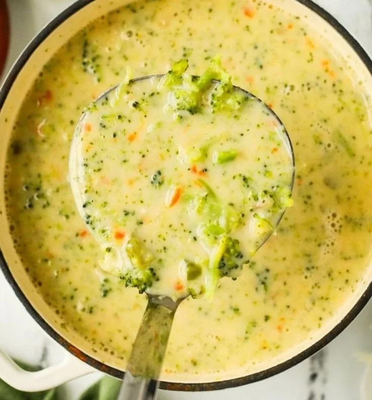 Bowl of protein-packed broccoli cheddar soup topped with cheese and broccoli florets