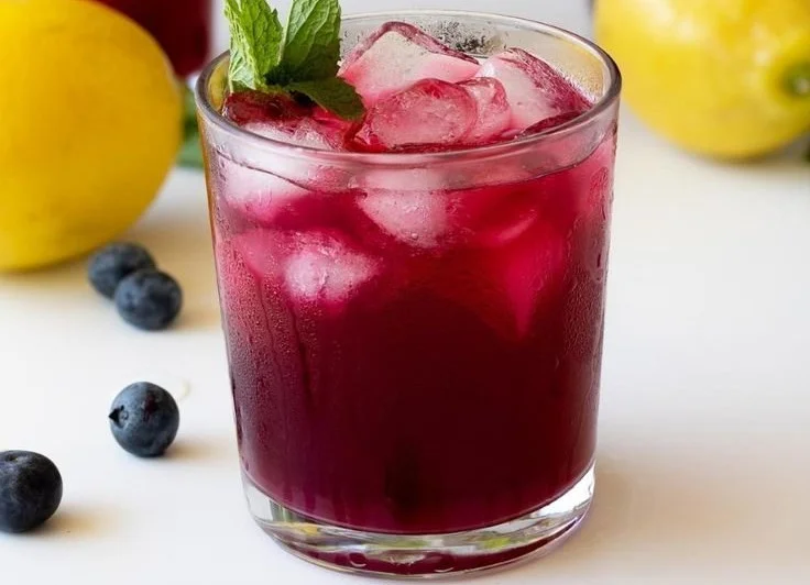 Glass of refreshing blueberry lemonade with blueberries and lemon slices