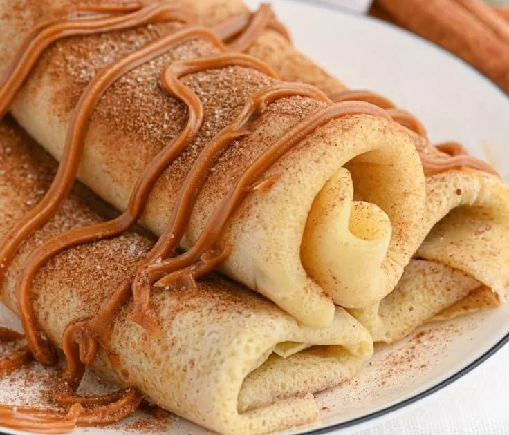 Delicious cinnamon roll protein crepes drizzled with icing on a plate