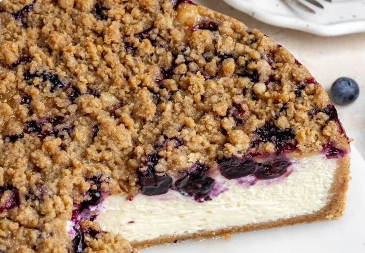Slice of creamy blueberry cheesecake topped with fresh blueberries