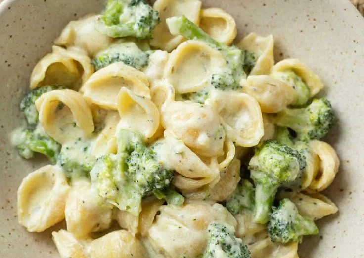 Creamy broccoli pasta dish garnished with parmesan and herbs
