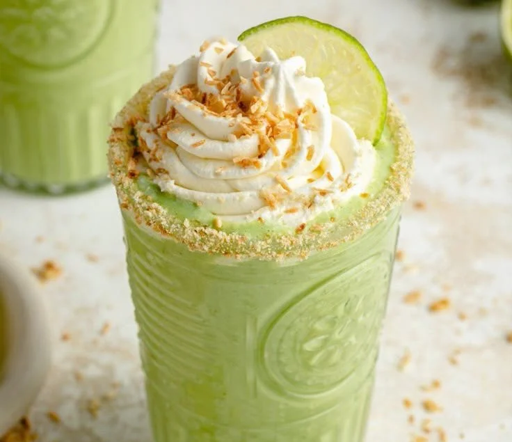 Creamy coconut key lime pie smoothie topped with lime slices and coconut flakes.