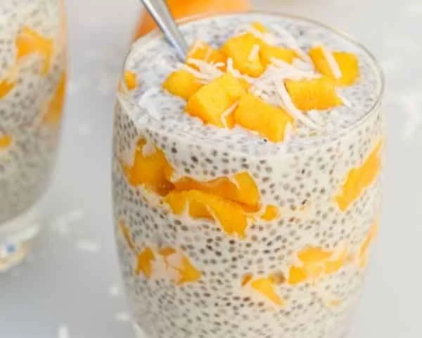 Fresh mango coconut chia seed parfait served in a glass with tropical toppings