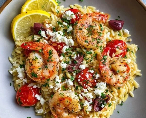 Lemon Feta Orzo Shrimp dish garnished with herbs and lemon slices.