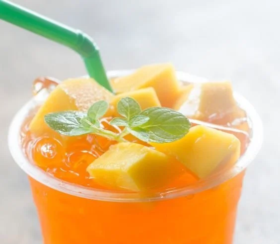 Refreshing Mango Iced Tea in a clear glass with fresh mango slices.