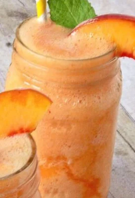 Delicious Peach Lemonade Slush in a glass with ice and fresh peaches