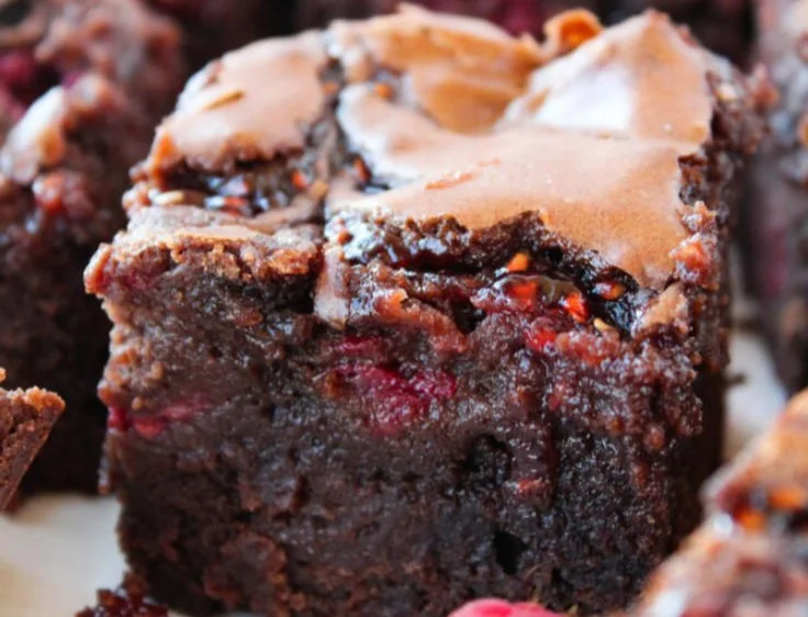 Delicious raspberry brownies topped with fresh raspberries and chocolate drizzle.