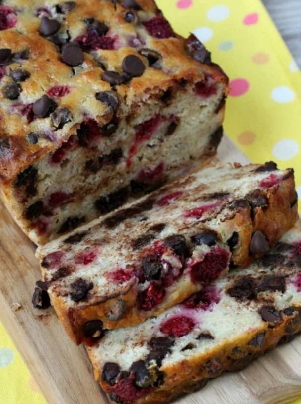 Raspberry Dark Chocolate Banana Bread with a slice on a wooden cutting board