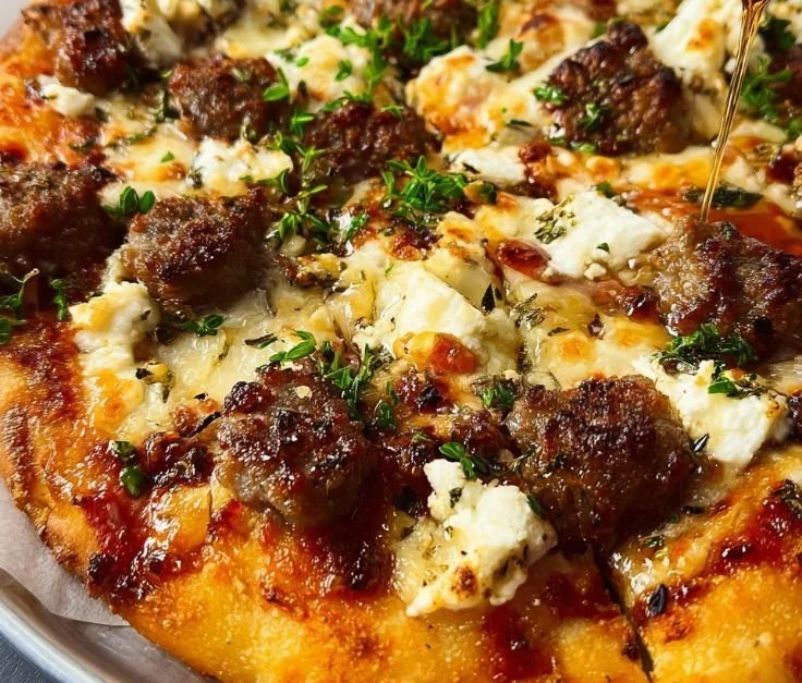 Sausage Ricotta Honey Hot Pizza slice with toppings on a wooden board