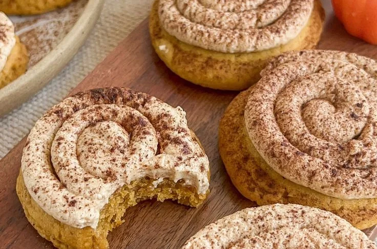 Soft pumpkin cookies with cinnamon frosting on a white plate.