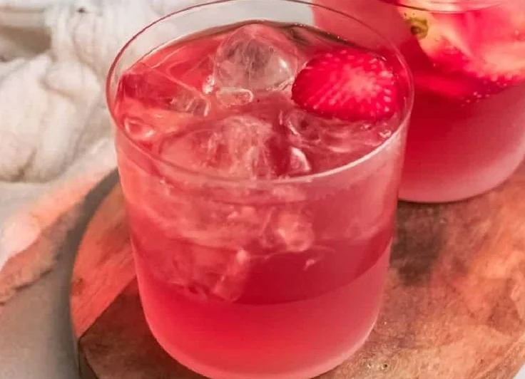 Glass of strawberry iced tea with fresh strawberries and mint leaves