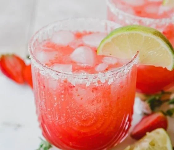 A vibrant Strawberry Lime Mocktail Margarita in a glass, garnished with lime and strawberries.