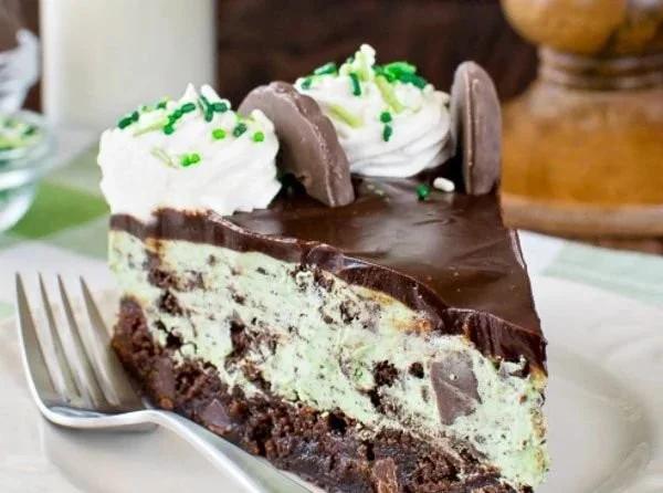 Thin Mint Cheesecake Brownie Cake topped with mint chocolate and creamy cheesecake layer